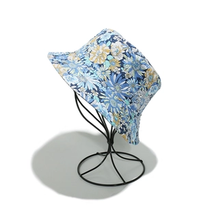 Detail of blue floral sun hat with sunflower pattern on a black metal head display stand