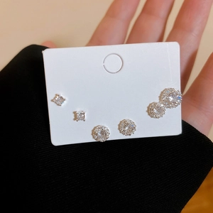 Detailed view of three pairs of silver-plated zircon stud earrings on a display card