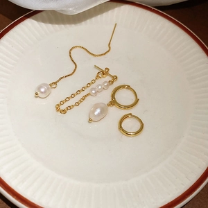 Detail of four-piece gold earring set with freshwater pearls on a white ceramic plate
