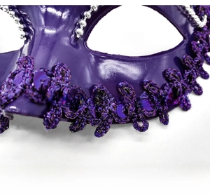 Detail of purple Venetian masquerade mask with glitter sequins and silver braided trim