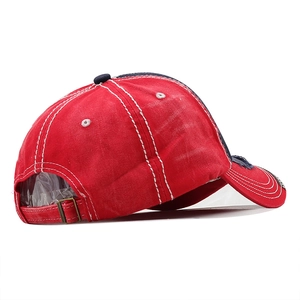 Close-up of vintage red washed cotton baseball cap with white stitching and metal buckle