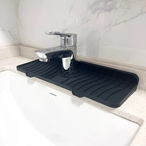 Detail of black silicone faucet draining mat with wavy texture on white countertop