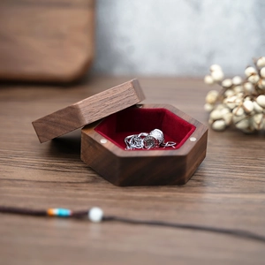 Detailed macro view of a hexagonal walnut jewelry box with a red velvet interior