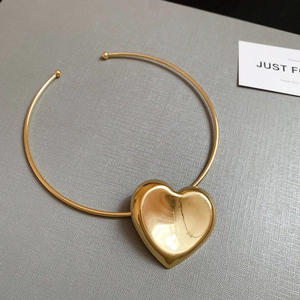 Detail showing high-polish gold choker necklace with a large 3D heart-shaped pendant