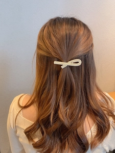 Macro detail of a twisted bow hair clip featuring elegant inlaid mini pearls on hair
