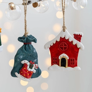 Resin Christmas ornaments featuring blue gift bag and red snowy house with hanging ropes