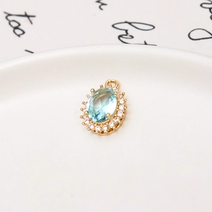 Macro detail of oval light blue crystal pendant with micro-set zircon on white porcelain