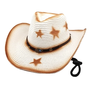 Detail of white cowboy hat featuring star patterns and Hand of Fatima pendant charm