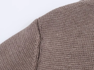Macro shot of precise seams and dense knit texture on brown knitted cardigan