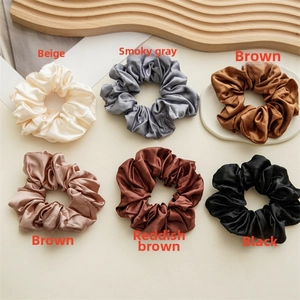 Flat lay of six premium satin silk scrunchies in various neutral and earthy tones
