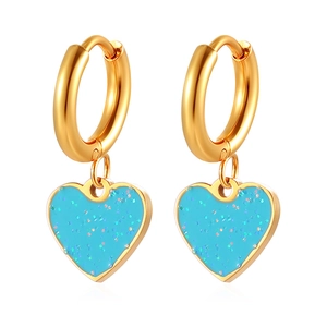 Gros plan de boucles d'oreilles cœur dorées avec pendentifs pailletés bleus étincelants
