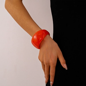 Close-up of a wide translucent red acrylic geometric bangle on a woman's wrist