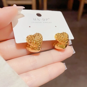 Detailed macro view of heart-shaped hollow mesh earrings in elegant gold finish