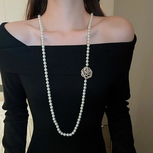 Vue détaillée d'un collier de perles long avec pendentif rose dorée évidée