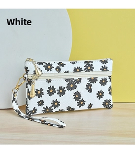 Macro detail of a white floral daisy pattern canvas wallet with gold zipper and wrist strap