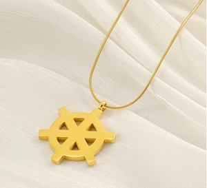 Detailed view of 18K gold-plated rudder pendant on sleek snake chain over white silk fabric