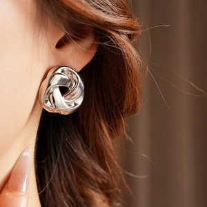 Gros plan d'une boucle d'oreille en nœud argenté portée par un mannequin chic