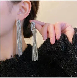 Detail of silver long tassel earrings with snake chains held against black sweater