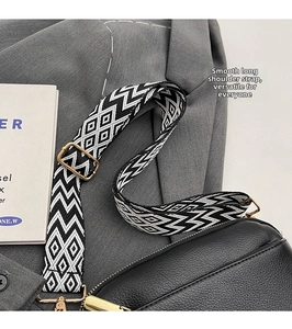Detail of adjustable black and white geometric woven strap on a black PU leather crossbody bag