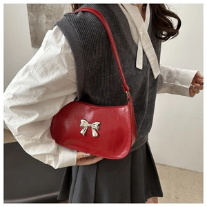 Close-up of a vibrant red underarm bag featuring a silver metal butterfly buckle detail