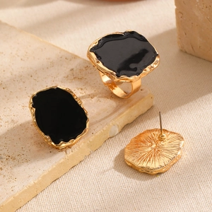 Detailed view of vintage gold-rimmed ring and earrings set with black enamel drip finish