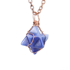 Macro detail of hand-woven bronze wire wrapping a blue star-shaped agate pendant