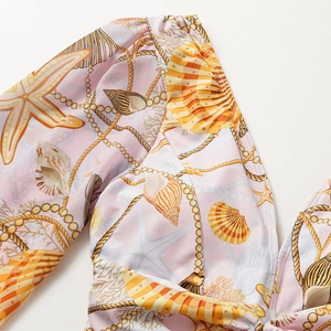 Close-up of pink long-sleeve swimsuit featuring sea stars and pearl patterns
