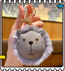 Detail of grey plush lion keychain featuring faux fur mane and gold metal hardware clasp