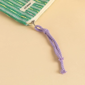Close-up of green knitted cosmetic bag with textured weave and purple zipper puller