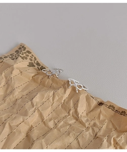 Close-up of S925 sterling silver bow rings with twist texture on vintage kraft paper
