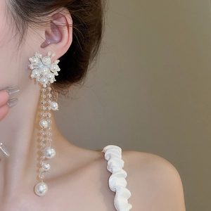 Detailed close-up of elegant pearl flower earrings with long shimmering tassel strands