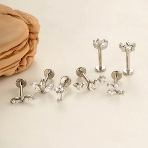 Set of 6 minimalist stainless steel labret studs with marquise zirconia on a beige surface