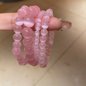 Detail of pink cat-eye stone beaded bracelets showing light-reflecting layers and luster
