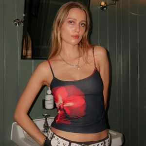 Detail of red floral print on cropped slim camisole against a striped bathroom wall