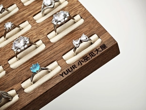 Macro view of crystal and blue gemstone rings displayed on a premium walnut tray