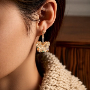 Close-up of golden butterfly crystal pendant earrings worn with autumn sweater