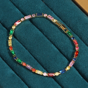 Macro shot of colorful zircon stones on gold plated bracelet displayed on green velvet tray
