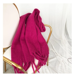 Close-up of soft magenta cashmere-feel scarf with thick tassels draped on a white chair