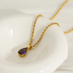 Detailed macro view of 18K gold plated rope chain with purple teardrop gemstone pendant