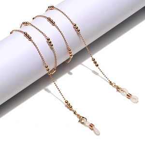 Golden beaded metal eyewear chain with silicone loops shown on white display stand