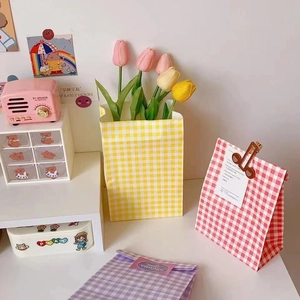 Colorful gingham checkered paper gift bags with decorative stickers and wooden clips
