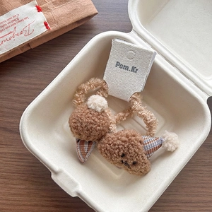 Detail view of two plush teddy bear hair scrunchies with party hats in a gift box