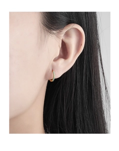 Close-up of gold hoop earrings with turquoise stones worn by a model in a natural setting
