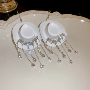 Detail of white cowboy hat earrings with rhinestone tassels and teardrop crystal drops