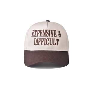 Close-up of the detailed 'EXPENSIVE & DIFFICULT' embroidery on a two-tone cotton baseball cap
