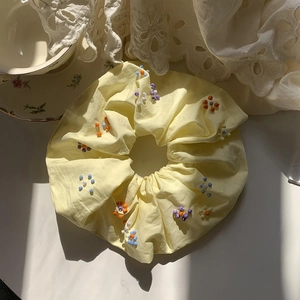 Dettaglio di un elastico per capelli in tessuto giallo con perline su pizzo bianco