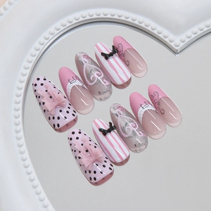 Pink French cat-eye press-on nails with 3D bows, lace patterns, and floral dot designs