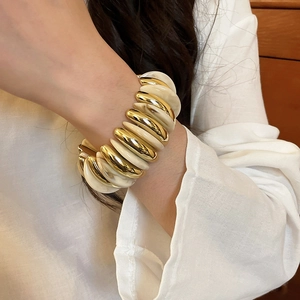 Detailed close-up of acrylic resin and gold metal stretch bracelet on a female wrist