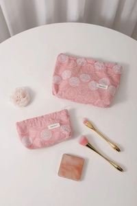 Detail of pink cotton cosmetic bags with white floral embroidery and zipper closure