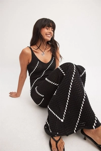Detailed close-up of crochet hollow-out pattern and zigzag stripes on a black maxi dress